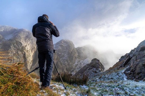 A photographer taking a photo with the tripod in the snowy winter sunset