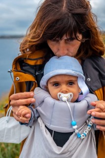A young mother with her baby at the Phare Du Cap Frehel is a maritime lighthouse in Cotes-dÂ´Armor France . At the tip of Cap Frehel
