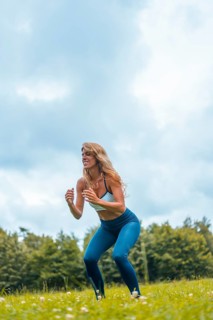 Fitness session with a young blonde caucasian woman exercising in nature with a blue maya on her feet and a white short shirt. Squatting and jumping