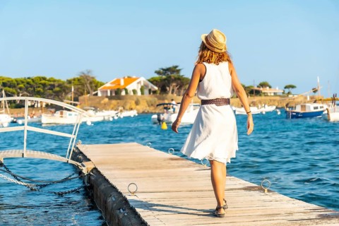 A young woman in a dress in Cadaques walking along the sea