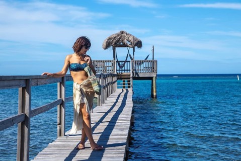 A young girl on a wooden walkway above the Caribbean Sea on Roatan Island. Honduras