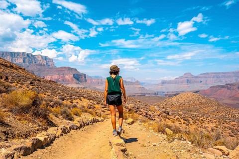 A young woman with green shirt resting on the South Kaibab Trailhead trekking. Grand Canyon