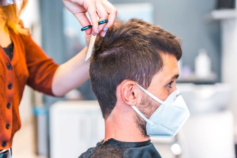 Hairdressers after the Coronavirus pandemic. Hairdresser with face mask and protective screen