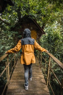A young woman in a yellow jacket visiting a haunted house in a forest. Mystical photography