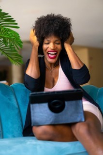 Young entrepreneur of black race and afro hair making a video call with great joy and amazement