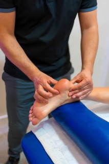 Physiotherapeutic massage to an unrecognizable woman lying on a stretcher on the foot