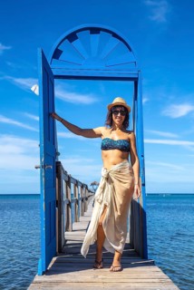 A young girl at a blue door in the Caribbean Sea on Roatan Island. Honduras