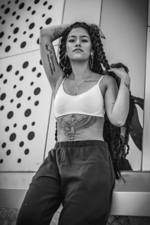 Young woman of black ethnicity with long braids and with tattoos