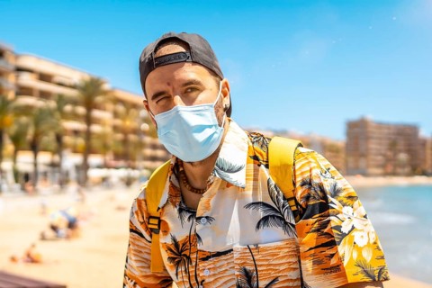 A young man with a tourist surgical mask on the Cura beach in the coastal city of Torrevieja