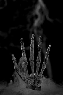 Skeleton hand in front of artificial cobwebs