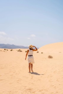 A young tourist wearing a hat walking along the sand on the beaches of the Corralejo Natural Park