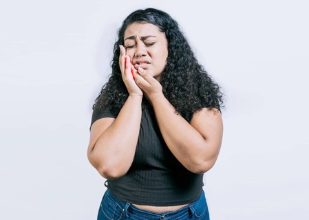 Young woman suffering with toothache isolated. Girl rubbing cheek with toothache on white background