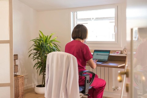 Rear view of a female doctor using laptop working from a home office