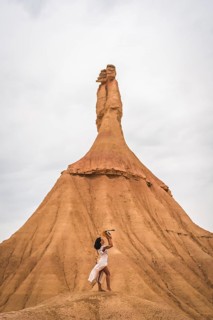 Young brunette Caucasian girl with a white dress and a straw hat in the Castildetierra of the Bardenas Reales desert
