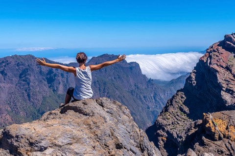 A young woman sits resting and looking at the views of the Roque de los Muchachos national park on top of the Caldera de Taburiente