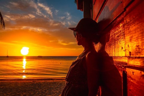 A young woman with a cap at Sunset on West End Beach