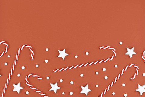 Christmas flat lay with candy canes and star and snow ornaments on brown background with empty copy space