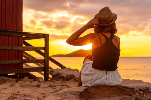 Young woman with hat at sunset in Cala Comte beach on the island of Ibiza. Balearic