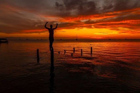 A young man in the water at the Orange Sunset on the West End beach of Roatan. Honduras