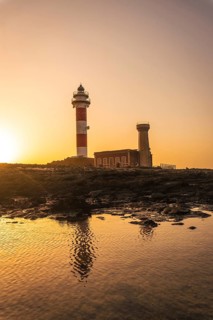 Sunset at the Toston Lighthouse near the sea with the reflected lighthouse
