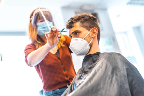 Hairdressers after the Coronavirus pandemic. Hairdresser with face mask and protective screen