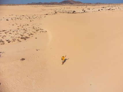Aerial view of a young man flying the drone in the dunes of Corralejo Park