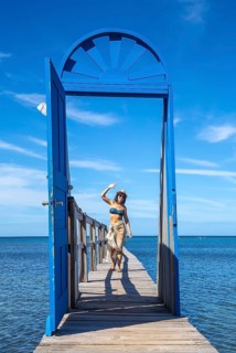 A cheerful young girl at a blue door in the Caribbean Sea on Roatan Island. Honduras