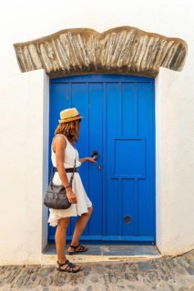 A young woman in a white dress in Cadaques on a blue door