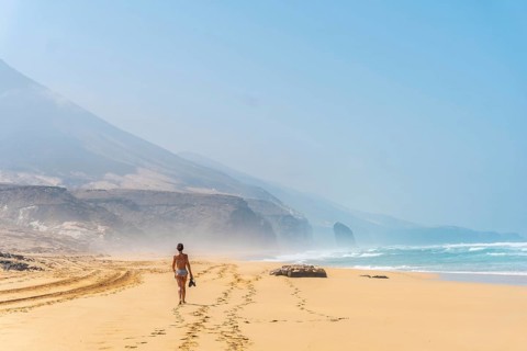 A young woman on the wild beach Cofete of the natural park of Jandia