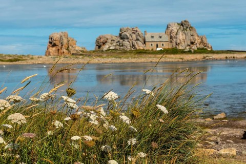 House between rocks next to a beautiful lake