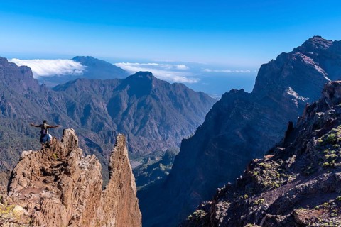 A young man after finishing the trek at the top of the volcano of Caldera de Taburiente near Roque de los Muchachos looking at the incredible landscape