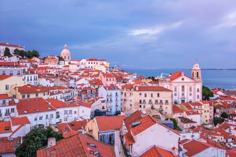 View of Lisbon famous view from Miradouro de Santa Luzia tourist viewpoint over Alfama old city district on sunset with dramatic overcast sky. Lisbon