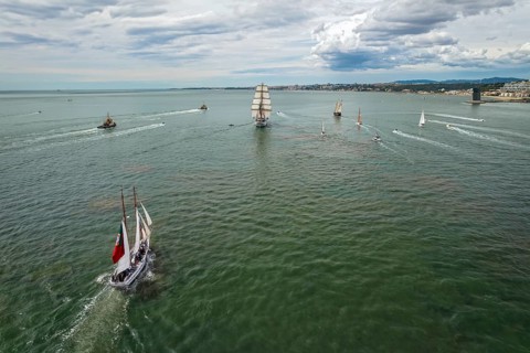 Aerial drone view of tall ships with sails sailing in Tagus river towards the Atlantic ocean in Lisbon
