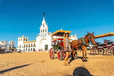 A tourist next to horses and carriages in the Rocio sanctuary in the festival of El Rocio in summer