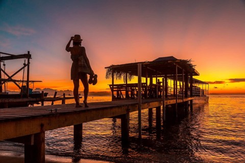 A young girl in a sunset on a pier on a beach on Roatan Island. Honduras