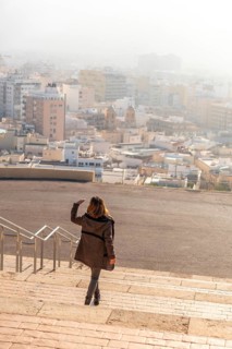 A young tourist on the stairs of the viewpoint of Cerro San Cristobal and the city of Almeria in the background