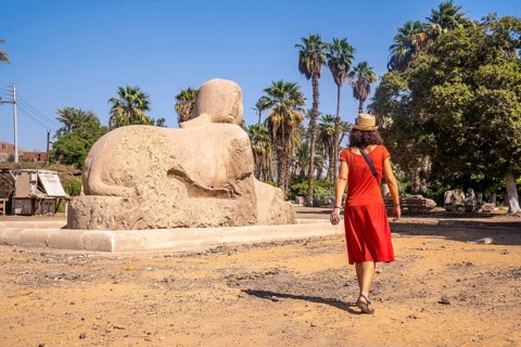 A young tourist in a red dress visiting the beautiful Sphinx of Memphis in Cairo