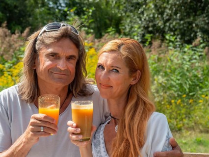 Man and woman in the garden with freshly squeezed fruit juice