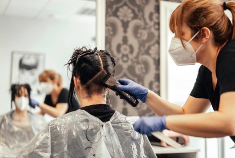 Hairdresser with mask and gloves shaving with razor. Reopening with security measures of Hairdressers in the Covid-19 pandemic