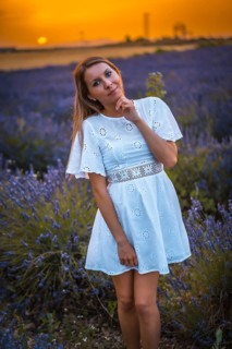 A young blonde Caucasian woman in a white dress in a cultivated lavender field in Navarra