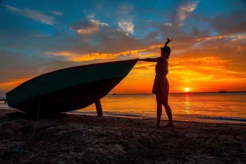 A young woman on the beach in a boat at Roatan Sunset from West End. Honduras