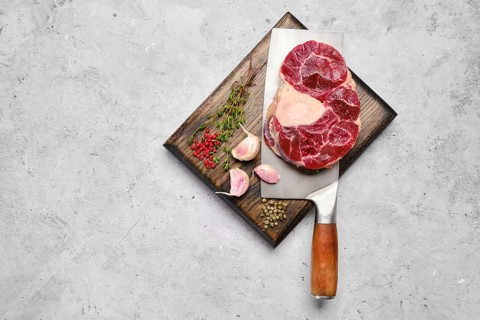 Top view of raw beef shank cross-cut on cleaver with spice and herb