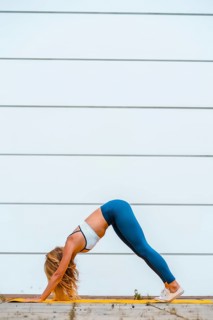 Yoga with blonde caucasian girl exercising on a yellow mat with a white wall in the background