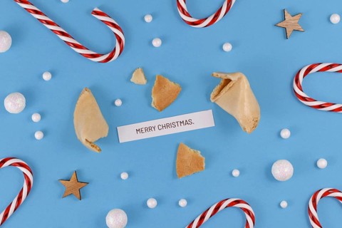 Christmas greetings with open fortune cookie and text 'Merry Christmas' on blue background with candy canes