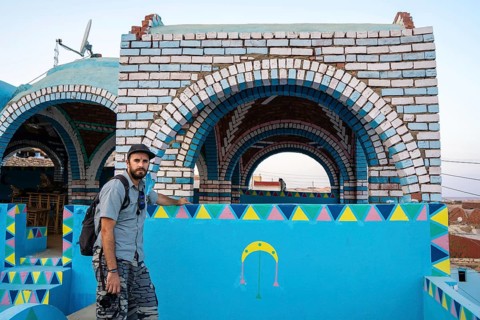 A young tourist sitting on a beautiful terrace of a traditional blue house in a Nubian village along the Nile river and near the city of Aswan. Egypt