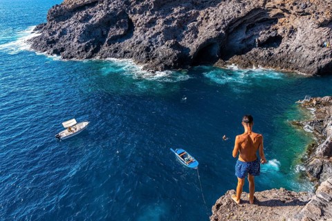 A young man making a very high jump into the water in the town of Poris de Candelaria on the north-west coast of the island of La Palma