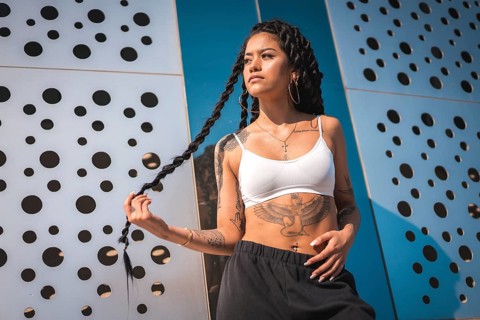 Young woman of black ethnicity with long braids and with tattoos
