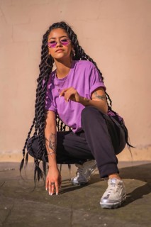 A dark-skinned young woman of Latin ethnicity with purple glasses in an urban session