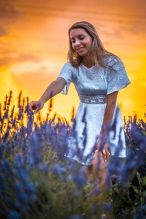 A young blonde Caucasian woman in a white dress in a cultivated lavender field in Navarra