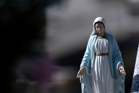 Kitschy figure of the Virgin Mary on a grave in a cemetery